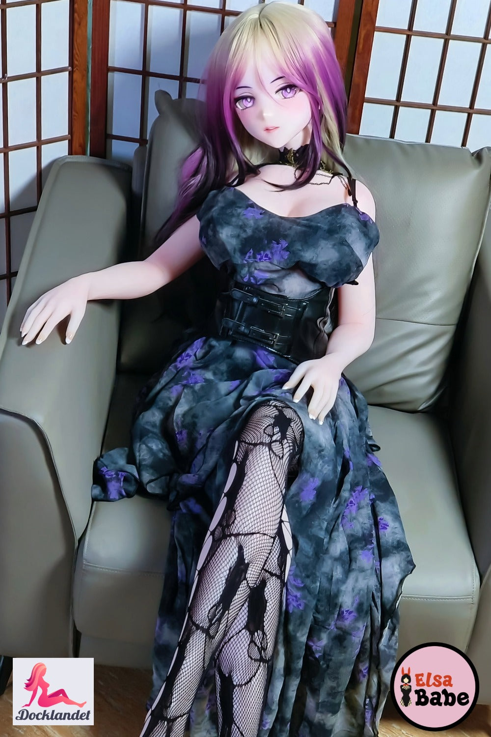 Elsa Babe Kitano Mina anime silikondocka sittande i fåtölj med svart och lila klänning, platinum-silikon och tydlig rock queen-stil.