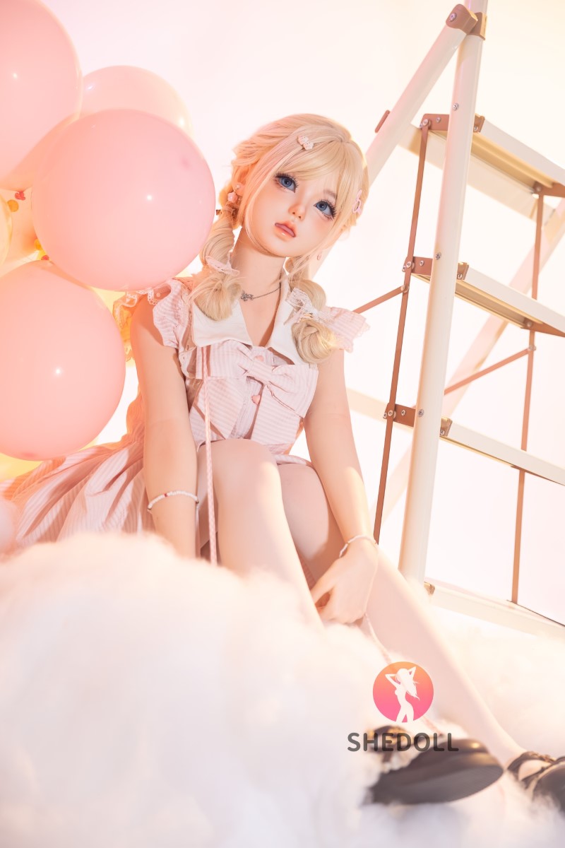 Sandy SHEDOLL 152 cm, helkropp sittande bland ballonger och rekvisita, rosa klänning, mjuk drömsk stil.